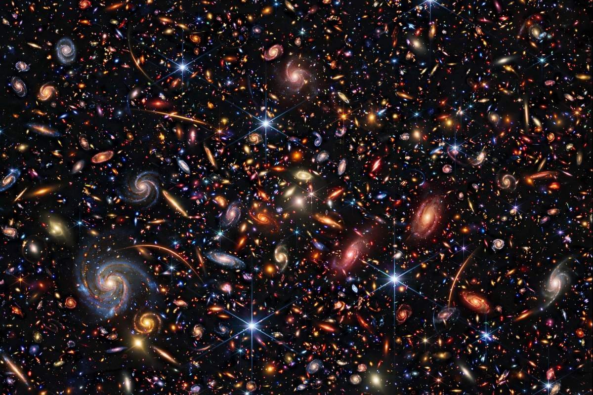 A deep-field view crowded with thousands of distant galaxies, showing how far space telescopes like Hubble and Webb can see.